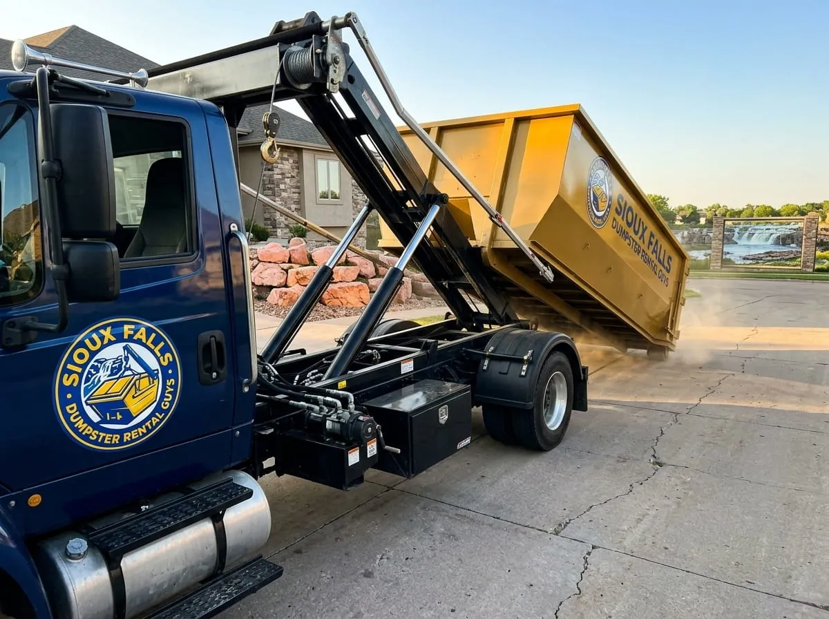 Sioux Falls Dumpster Rental Guys roll-off truck delivering a dumpster on a street in Sioux Falls, SD Sioux Falls Dumpster Rental Guys roll-off truck delivering a dumpster on a street in Sioux Falls, SD